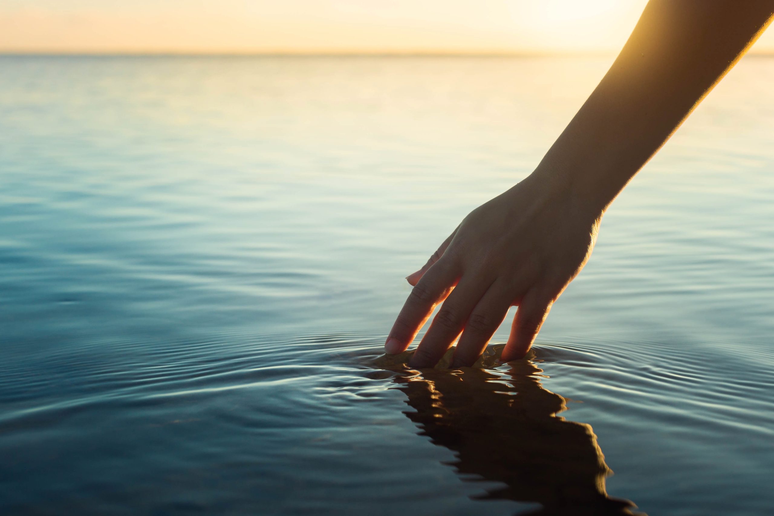 Happy people in nature. A woman feeling and touching the ocean w